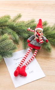 Detail of Christmas felt girl pendant with red scarf on wooden table with pine branches