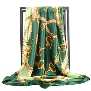 Green silk-like 90x90cm square scarf with gold chain and harness print displayed on stand
