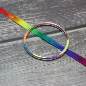 Close-up of flexible rainbow glitter jelly bracelets with colorful ribbon on wood base