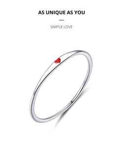 Dettaglio di un anello minimalista in argento S925 con un piccolo ciondolo a cuore rosso