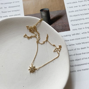 Detailed shot of an 18K gold plated star necklace with zircon inlays on a ceramic dish