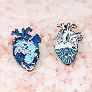Detail of two heart-shaped ocean enamel pins on pink crystals for creative jewelry lovers
