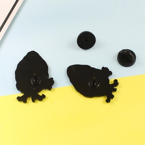 Detail view of heart brooch backings with two black rubber pin clutches on dual tone background