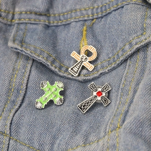 Lot de trois broches croix religieuses et ankh sur une veste en jean bleue