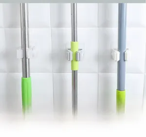 Detail showing adhesive mop holders with flexible arms holding various poles on tiles