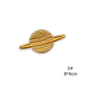 Macro view of gold and white planet embroidery patch with detailed Saturn rings texture