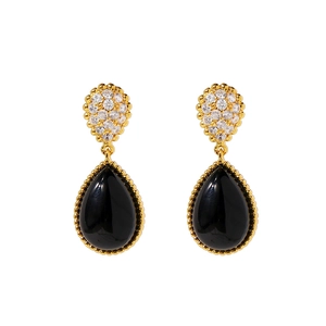 Detail of gold teardrop earrings featuring black stones and shimmering pave zirconias
