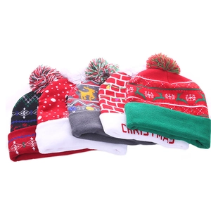 Stack of five festive LED Christmas knitted beanies with pom-poms on a white background