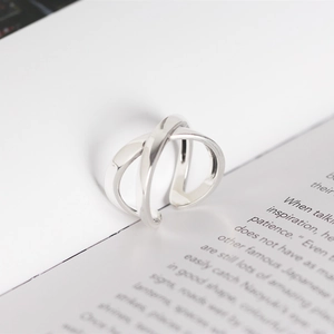 Detailed view of silver X-shaped crisscross ring on an artistic book background