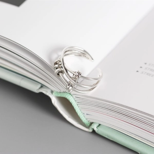 Macro shot of S925 sterling silver multi-layer cross ring with rotating beads on a book