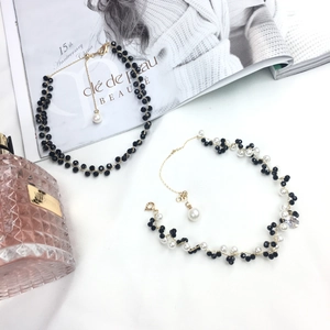Detail of beaded choker necklace with black crystal beads and white pearls on white cloth