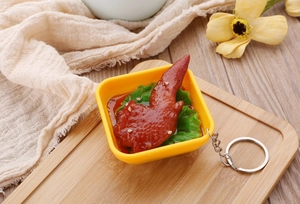Detailed view of realistic roasted chicken wing keychain model in a tiny yellow bowl