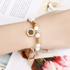 Elegant pearl and gold bead bracelet with crystal tree of life charm on a female wrist