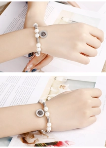 Detailed shot of pearl bead bracelet featuring a silver tree of life charm on a model's wrist