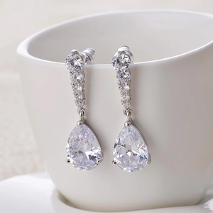 Elegant silver tassel earrings with teardrop cubic zirconia hanging on white ceramic cup