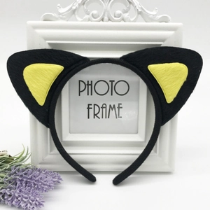 Detail of plush black cat ears headband with yellow inner lining on a photo frame