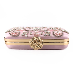 Close-up of pink satin evening clutch with handmade pearl beads and diamond rhinestones