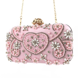 Detail of pink satin heart clutch with faux pearls, rhinestones and golden floral clasp