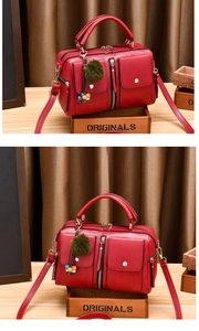 Close-up of red PU leather bag with multi-pocket design, green pompom and bead charm