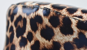 Detailed macro view of leopard print PU leather stitching and premium fabric texture