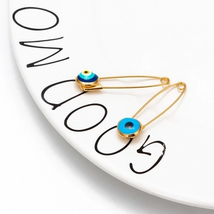 Detail of two gold evil eye pins on a white ceramic plate with minimalist decor
