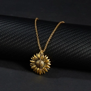 Macro shot of gold sunflower necklace pendant on a black textured cylinder display