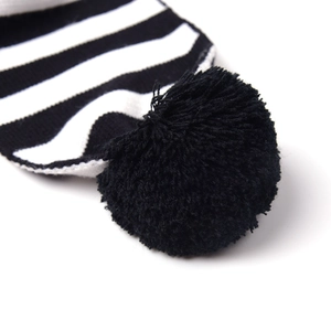 Bonnet tricoté à rayures noires et blanches avec un pompon noir duveteux sur le dessus