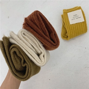 Close-up of thick knitted wool socks in dark green, beige, caramel, and mustard yellow