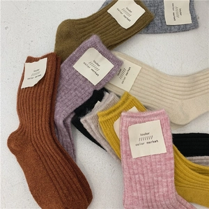 Close-up of colorful ribbed wool blend socks with minimalist tags in assorted earth tones