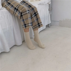 Detail of beige wool blend socks with vertical ribbed texture worn in a cozy setting
