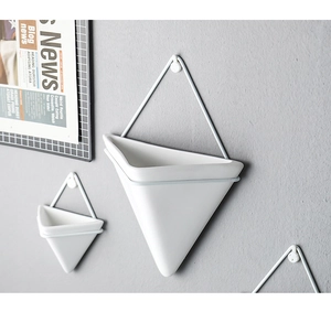 Detail of white geometric triangular wall planters with minimalist metal frames on grey wall