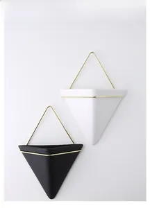 Detail of minimalist black and white triangular wall planters with golden metal hangers