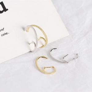 Detailed view of gold and silver huggie hoop earrings with cubic zirconia inlay