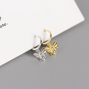 Detailed macro shot of 925 sterling silver bee pendant hoop earrings in gold and silver