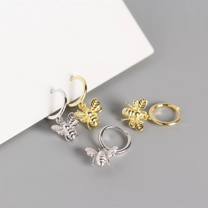 Detail view of gold and silver S925 sterling silver insect earrings with bee charms