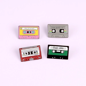 Set of four colorful retro 90s cassette tape enamel pins on a soft pink background