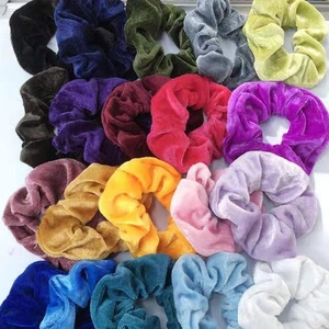 Detailed overhead view of fifteen colorful velvet scrunchies in assorted vibrant shades