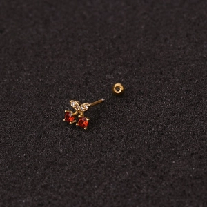 Detailed macro shot of golden cherry stud earrings with red and clear gemstones