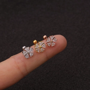 Three Zircon flower stud earrings in silver, gold, and rose gold on a fingertip