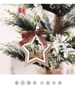 Detail of wooden star Christmas ornament with reindeer carving and plaid bow on pine branch