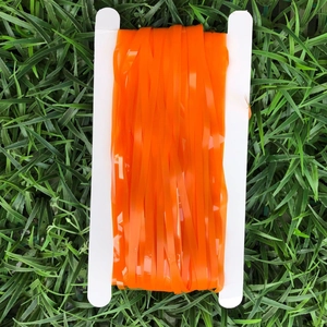 Detail of orange matte fringe curtain roll on white spool over green lawn background