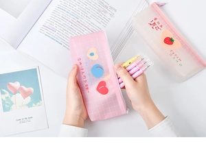 Detail showing pink checkered heart and white strawberry patterned pencil cases with zip