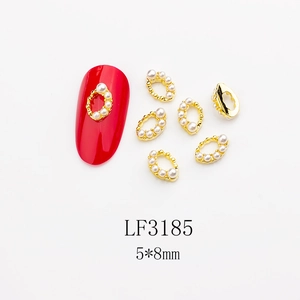 Detail of gold oval nail charm with white pearl LF3185 on a red nail sample