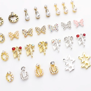 Macro detail of alloy nail charms with pearls, rhinestones, and butterfly shapes