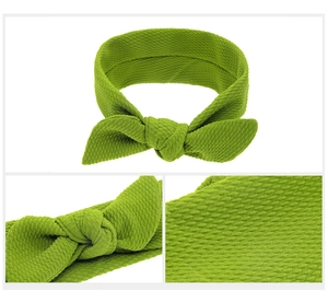 Detail view of bright green waffle knit baby headband featuring elastic rabbit ear bow