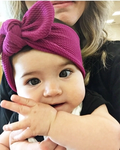 Macro detail of infant rose red headband featuring textured waffle knit fabric bow