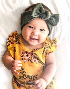 Baby girl in floral ruffle dress wearing an olive green waffle knit rabbit ear headband