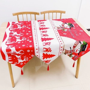 Close-up of Christmas table runners with reindeer, snowman designs and red fringe tassels