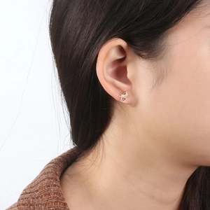 Close-up of a golden hollow cat stud earring with zircon eyes on a model's ear