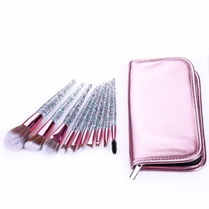 Macro view of 12 makeup brushes with pink storage bag and glitter sand handles